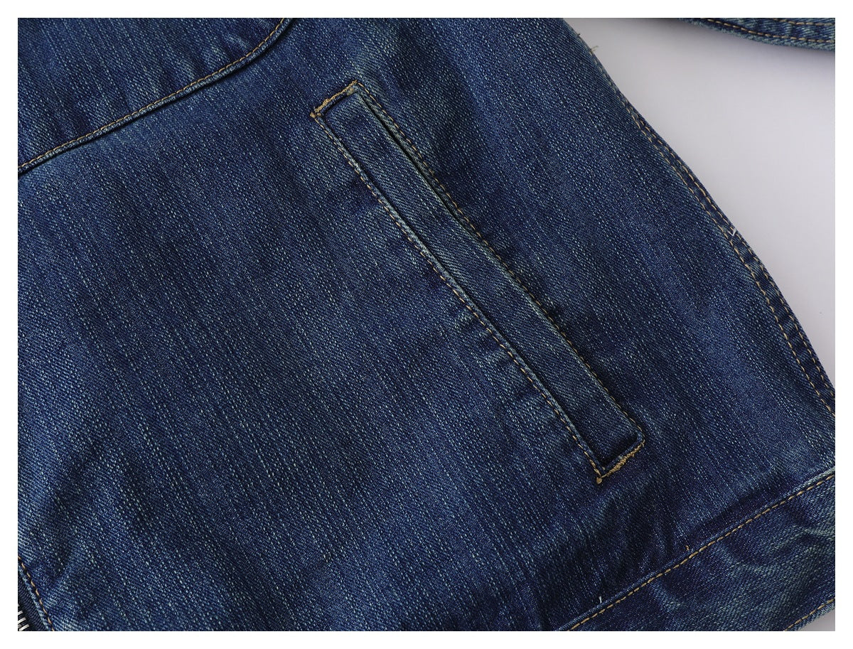 Close-up of a narrow slanted welt pocket on dark blue denim with tan stitching.