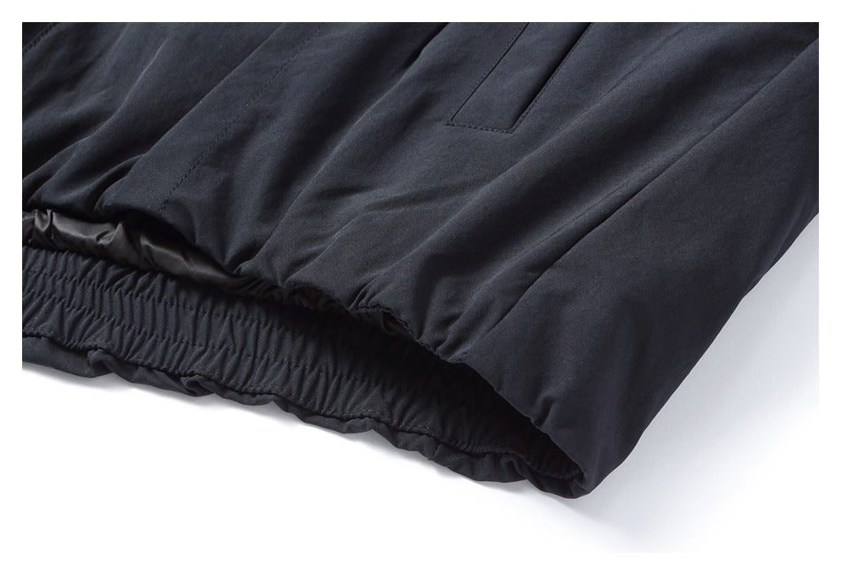 Close-up of dark trousers showing an elasticized hem and a pocket opening.