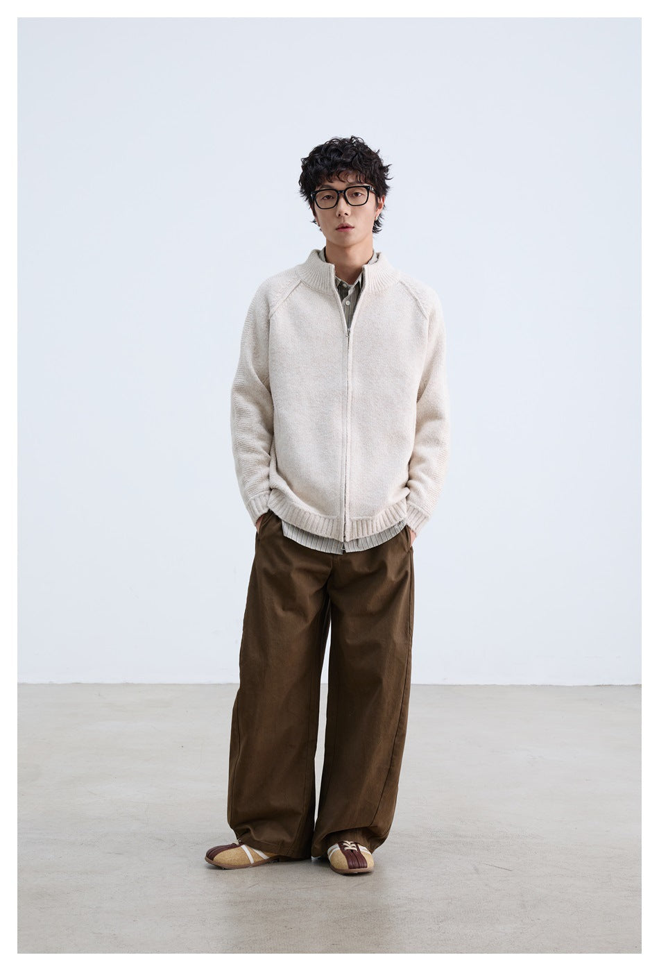 Full-length model wearing an off-white zip-front knit jacket with a stand collar and ribbed cuffs and hem.