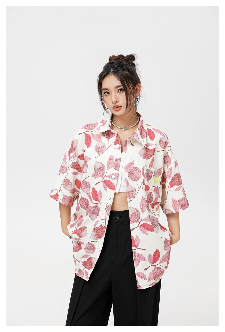 Closer view of a model wearing an ivory button-up shirt with a pink fruit-and-leaf print and a chest pocket.