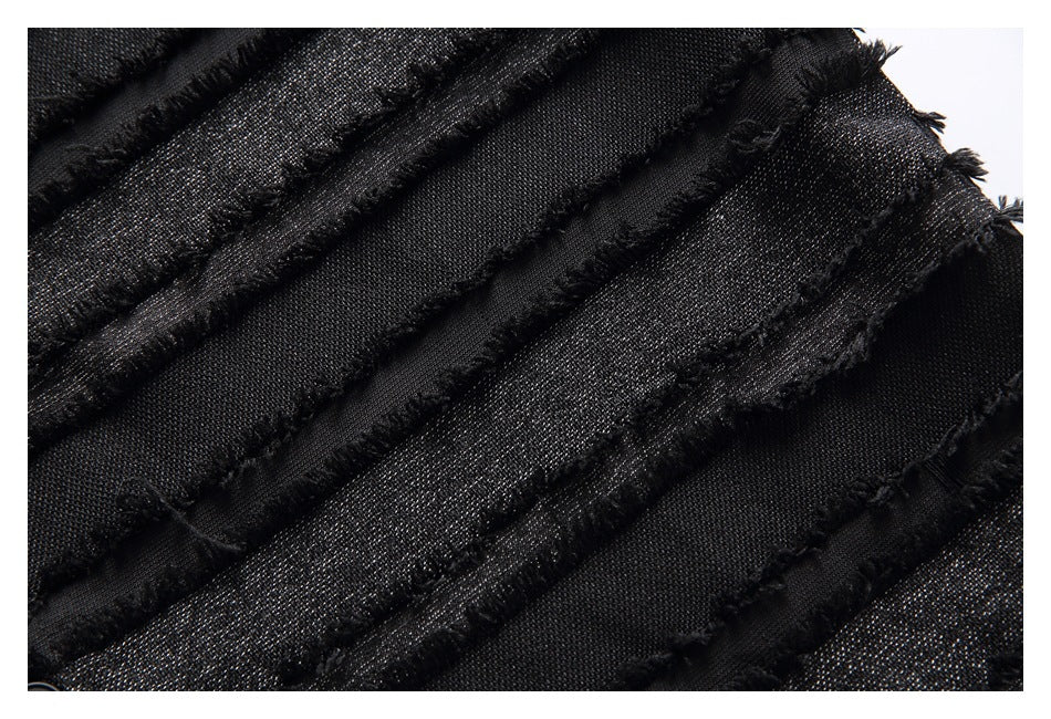 Macro view of black fabric with fine metallic flecks and parallel raised bands edged with fringe.