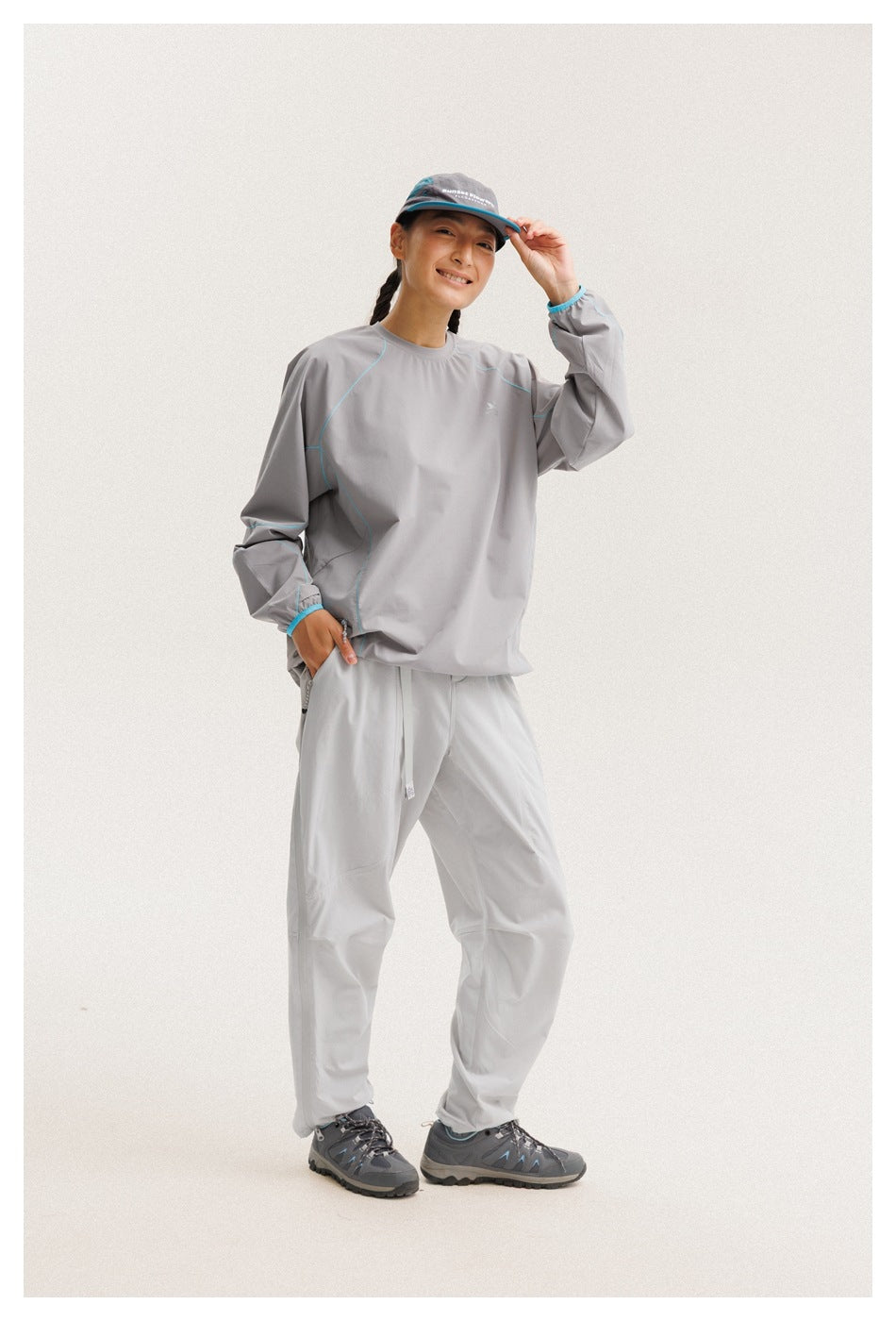 Model wearing a gray long-sleeve top with turquoise seam piping and matching light-gray pants, viewed from the front.