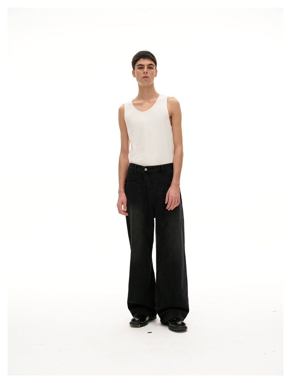 Model wearing a white sleeveless tank top and very wide black jeans, standing front-facing in a studio.