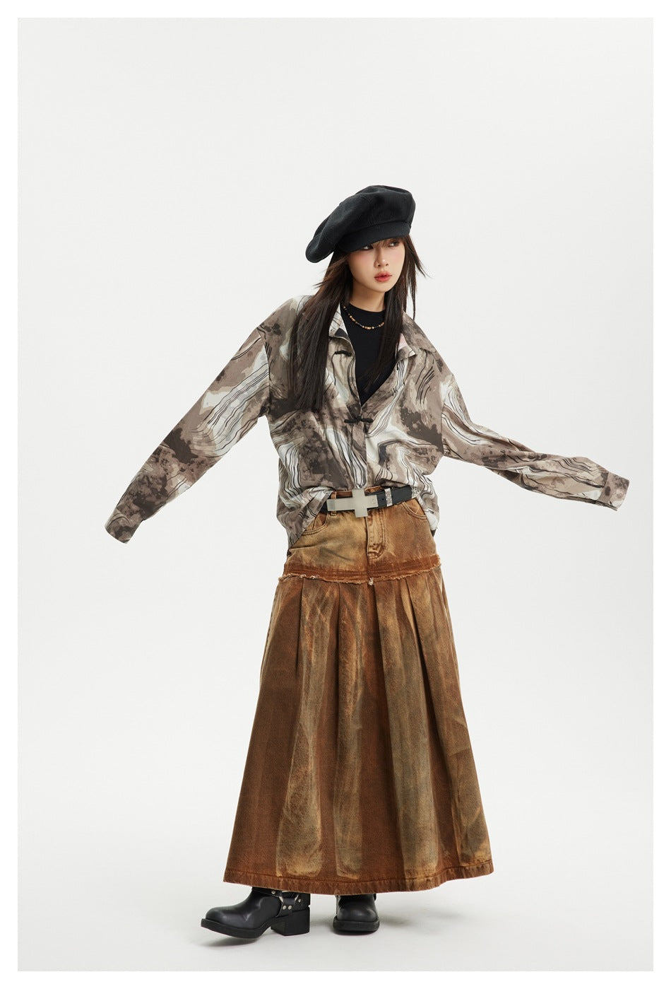 Model wearing the coffee ink-print shirt open over a black top with a black beret and a rust brown pleated skirt
