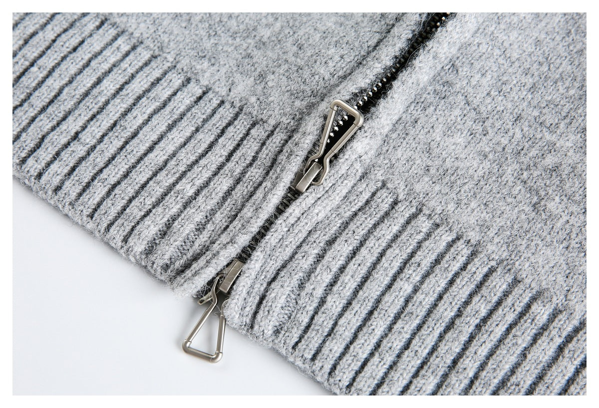Close-up of a metal zipper beside a dark gray ribbed edge on a light gray knit garment.