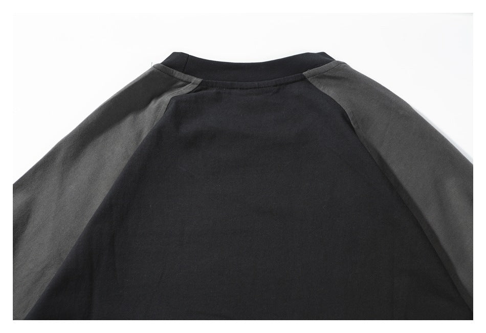 Close-up of a black garment's back neckline and shoulder seams, with charcoal-gray raglan sleeves.