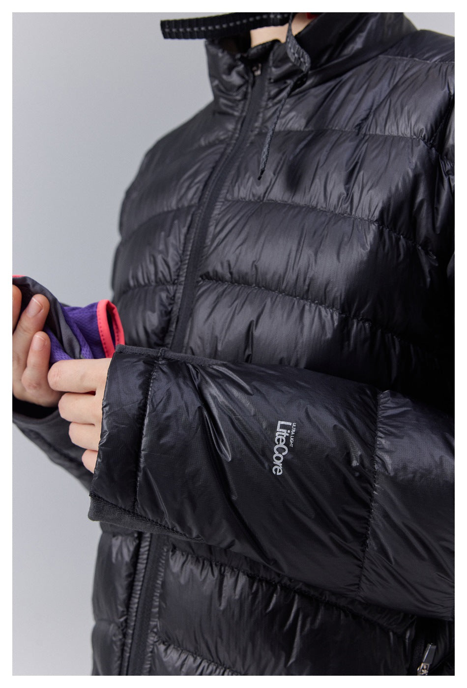 Close-up of a black quilted jacket showing its front zipper, padded sleeve, and small white ULCore cuff mark.