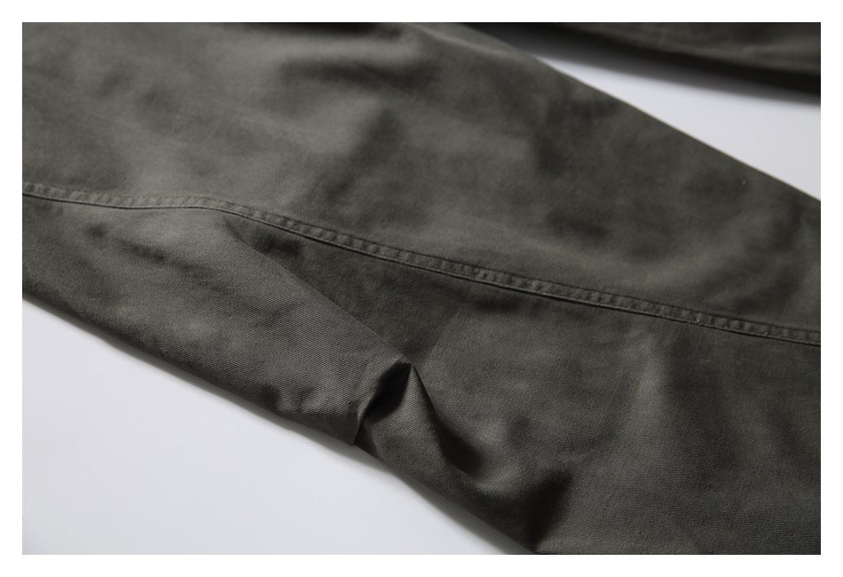 Close-up of a dark olive pant leg with a long stitched seam and subtle mottled shading.