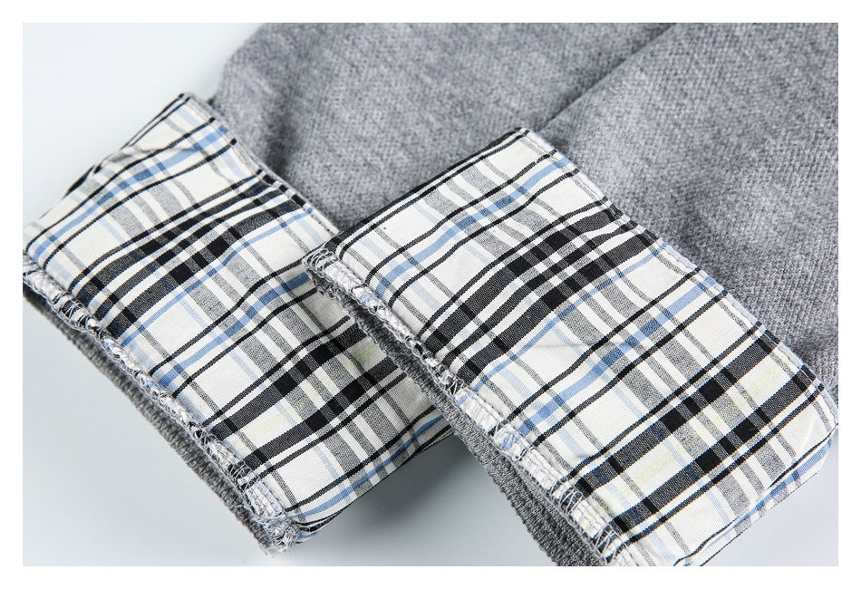 Close-up of gray garment cuffs with black, white, and blue plaid lining and visible overlocked edges.