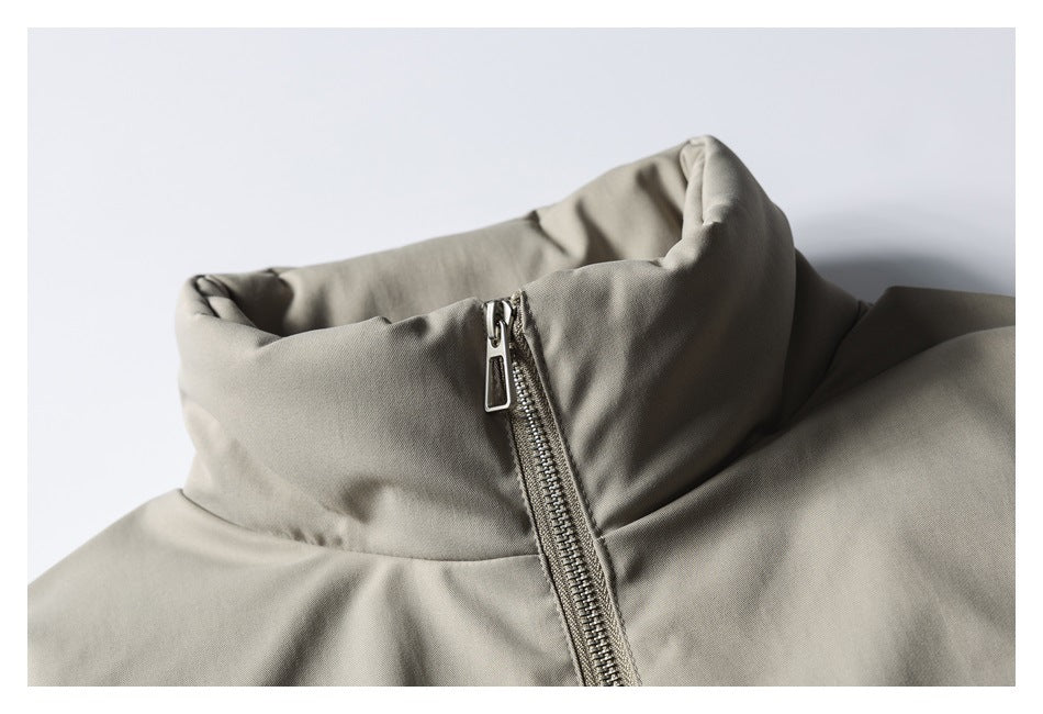 Close-up of a gray-beige jacket's tall stand collar and metal front zipper.