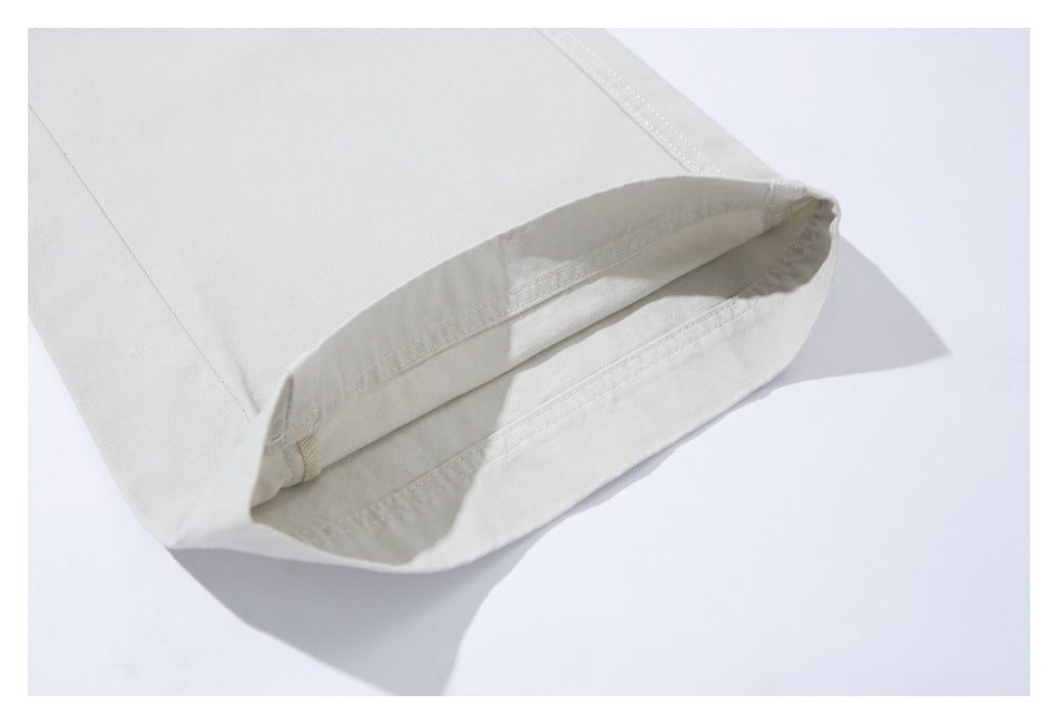 Close-up of an ivory trouser leg hem showing the folded edge and stitching.