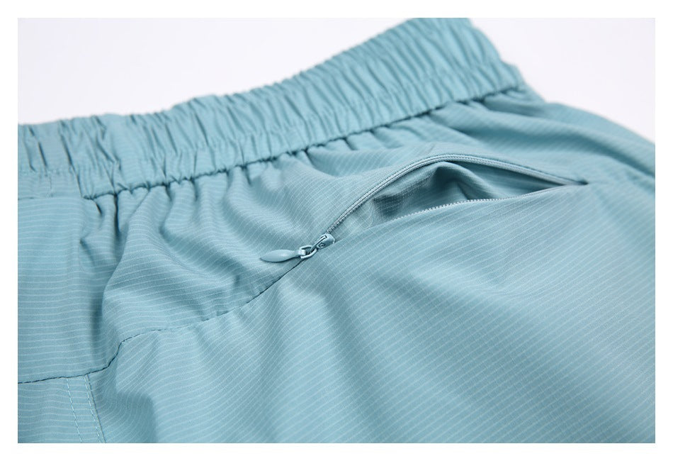 Close-up of an aqua shorts pocket with a zipper below the elastic waistband.