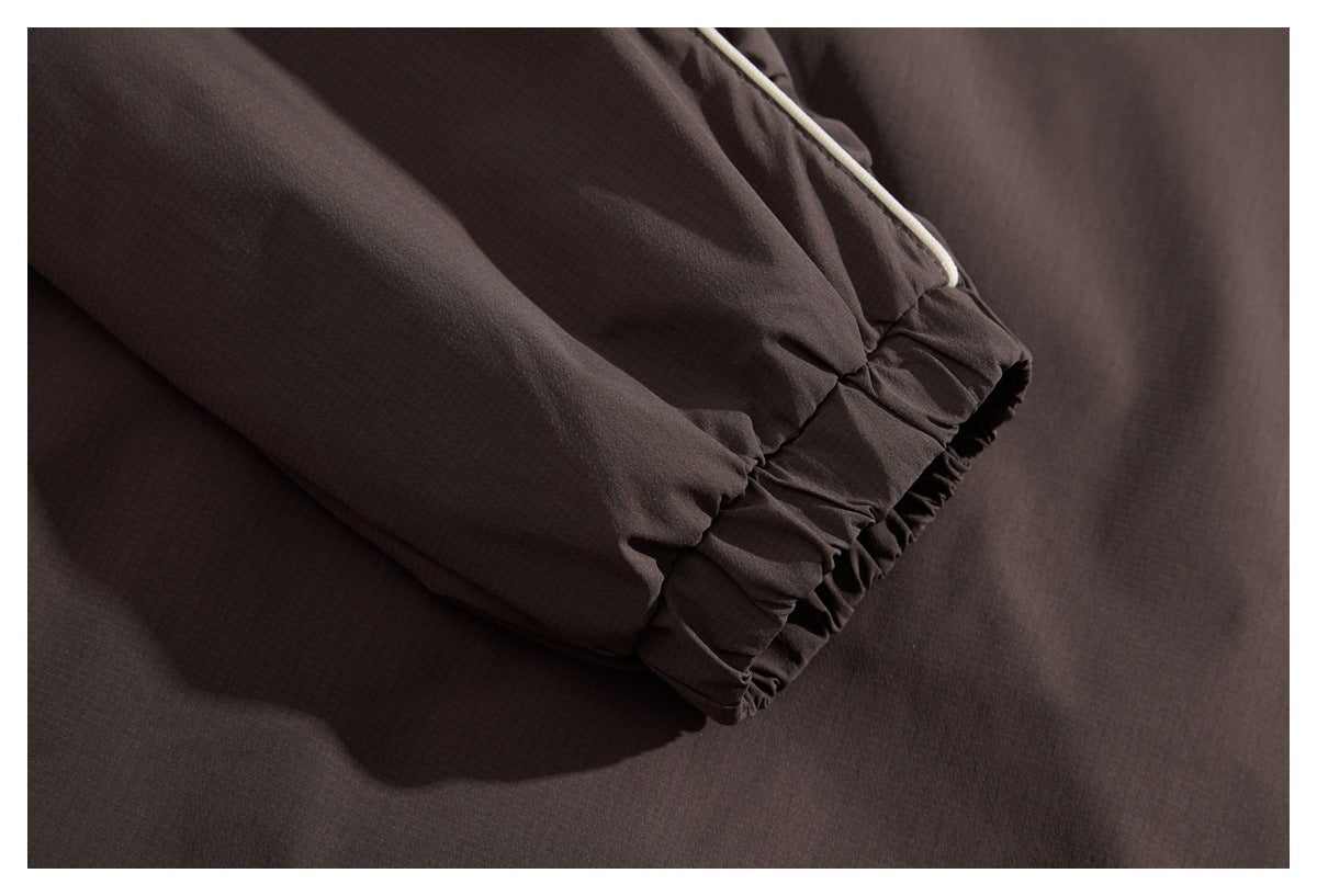 Close-up of a dark brown sleeve with a gathered elastic cuff and pale piping.