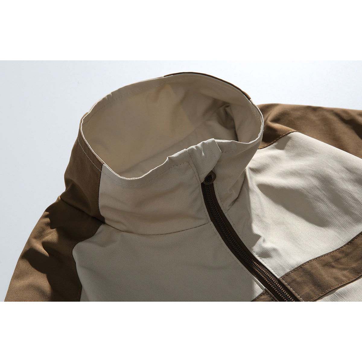 Close-up of a cream and brown color-block jacket collar, shoulder panels, and front zipper.