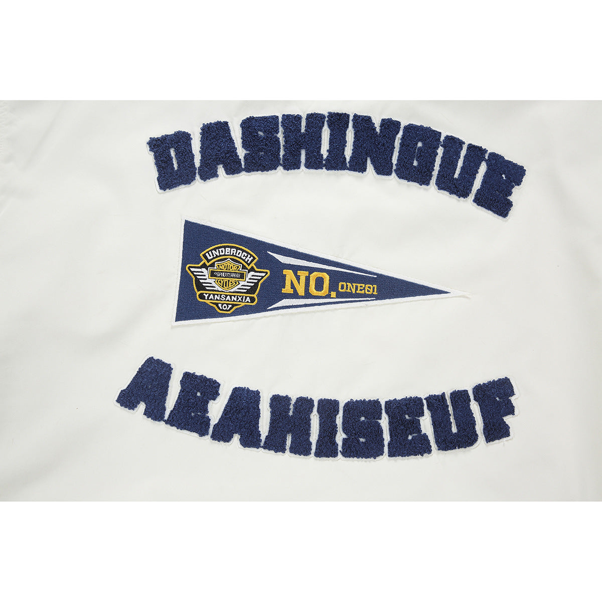 Close-up of navy embroidered lettering and a pennant-style patch on the cream jacket back.