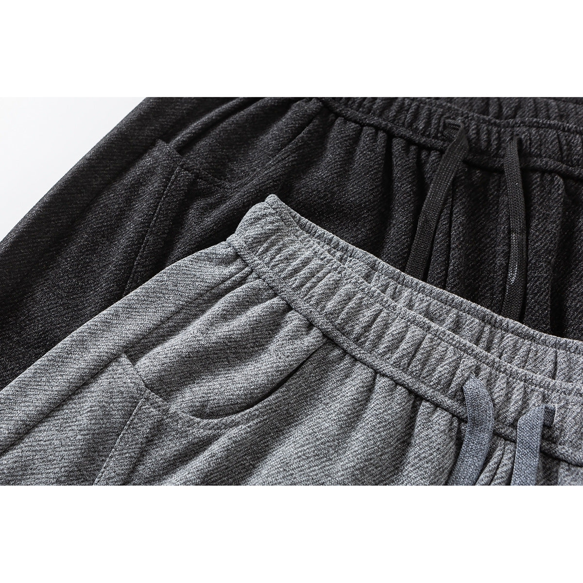 Close-up of charcoal and gray wide-leg pants showing elastic waistbands, drawstrings and side pockets.