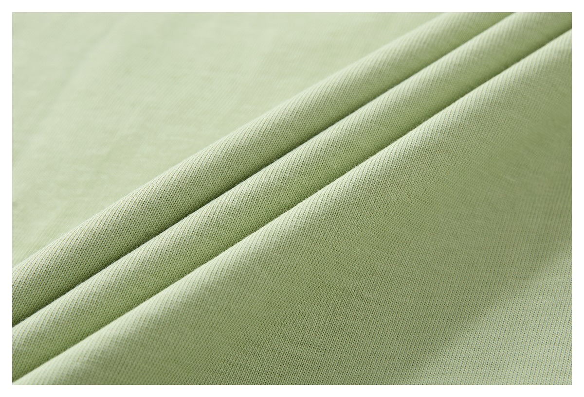 Close-up of pale green fabric draped in folds, showing its knit texture.