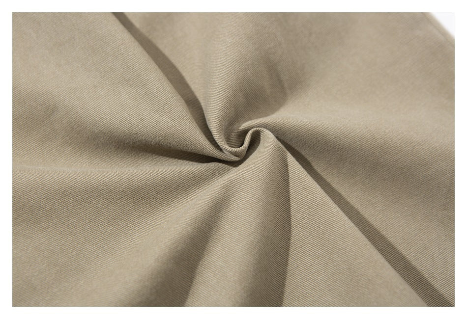 Close-up of khaki fabric gathered into a spiral, showing its diagonal weave.