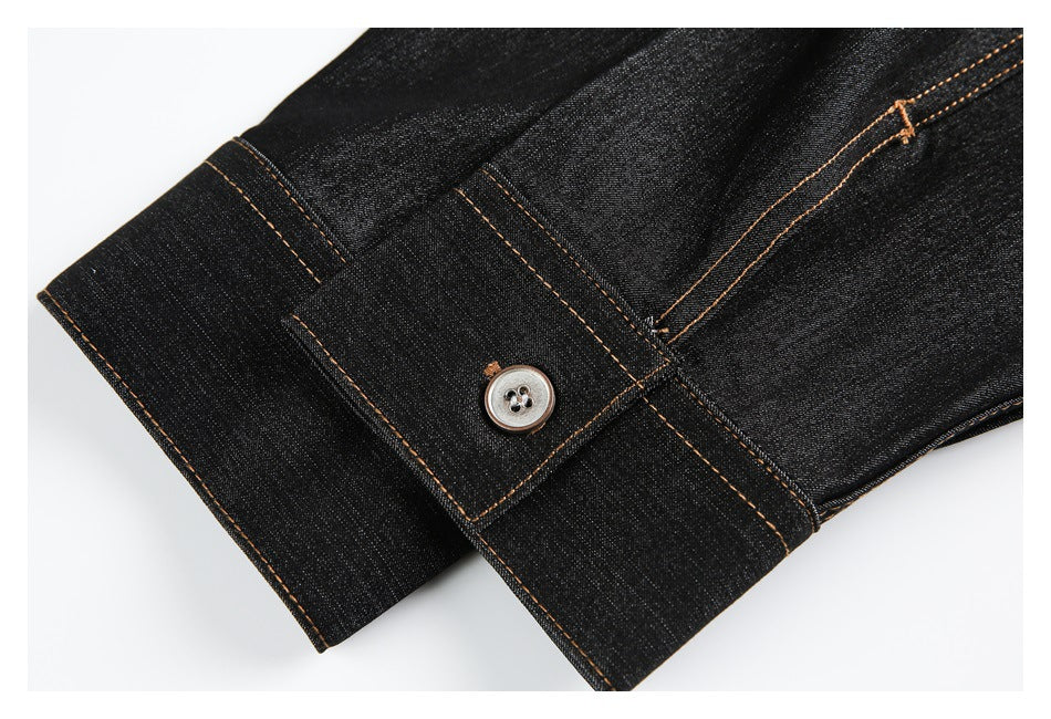 Close-up of a black denim shirt cuff with a silver button and tan topstitching.