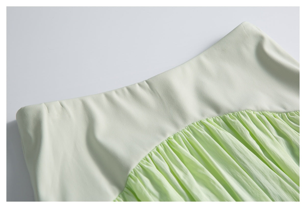 Close-up of the pale green skirt's smooth waistband and curved gathered seam.