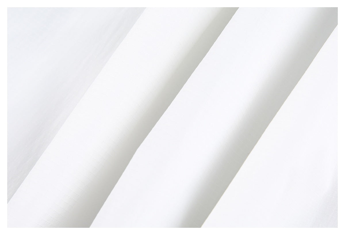 Close-up of white garment fabric with broad folded panels and subtle seams.