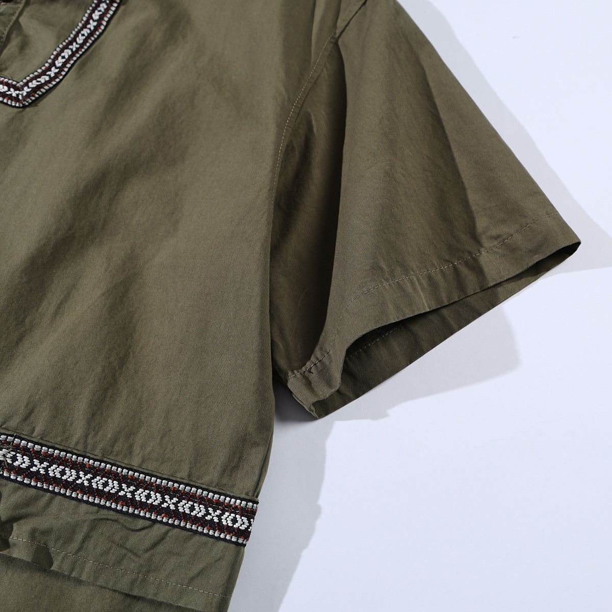 Close-up of an olive short-sleeve shirt with black, white, and rust geometric trim at the hem.