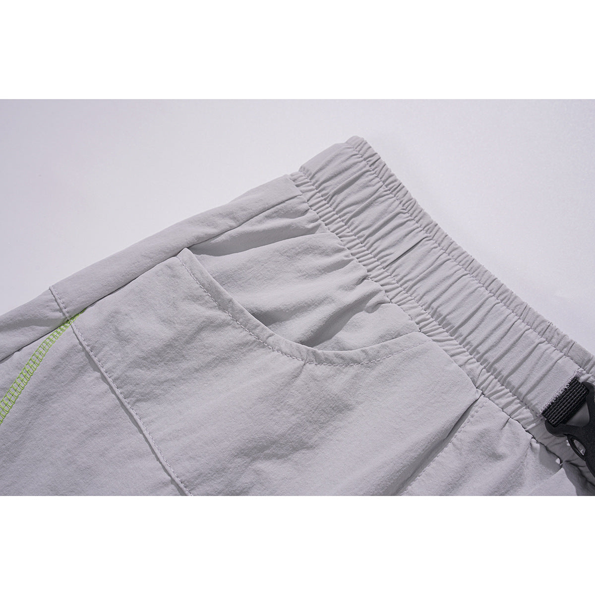 Close-up of a pale gray skirt's gathered elastic waistband and curved front pocket.