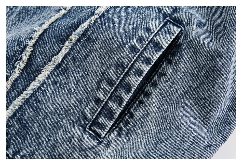 Close-up of blue acid-wash denim with a narrow stitched pocket opening and frayed seam.