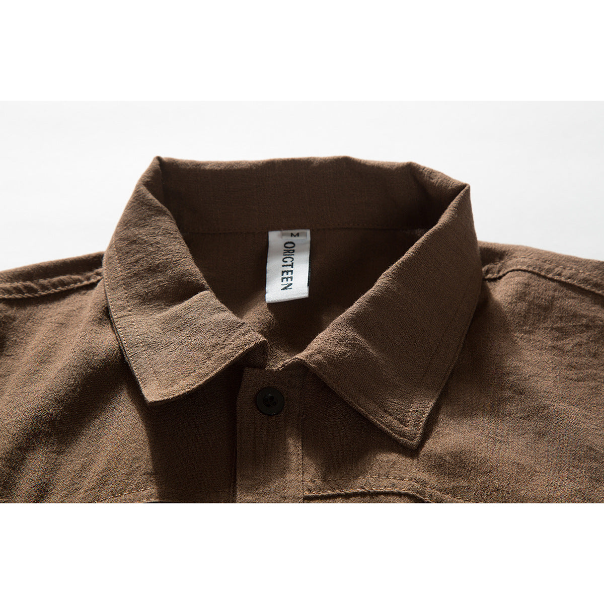 Close-up of a brown shirt collar, top button, and sewn neck label.