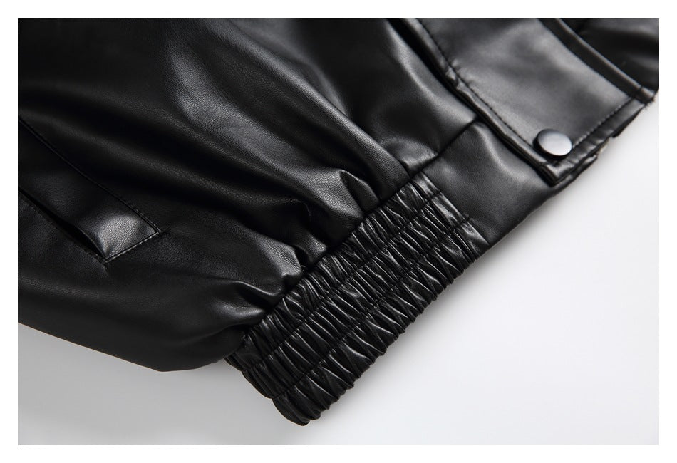 Close-up of a black jacket's gathered elastic hem, pocket opening, and snap-fastened flap.
