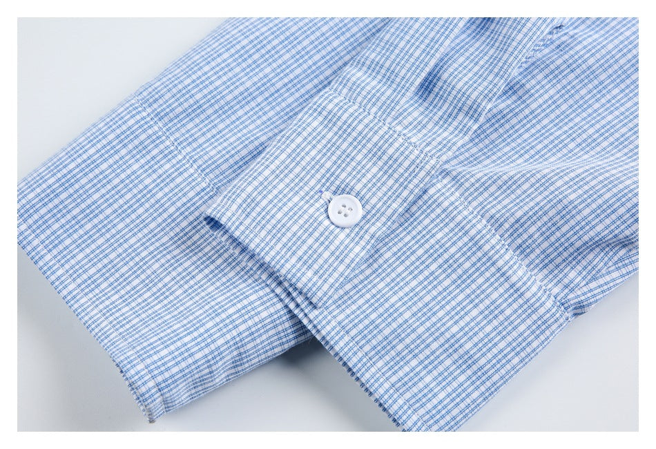 Close-up of a blue-and-white check shirt cuff with a white button and visible stitching.