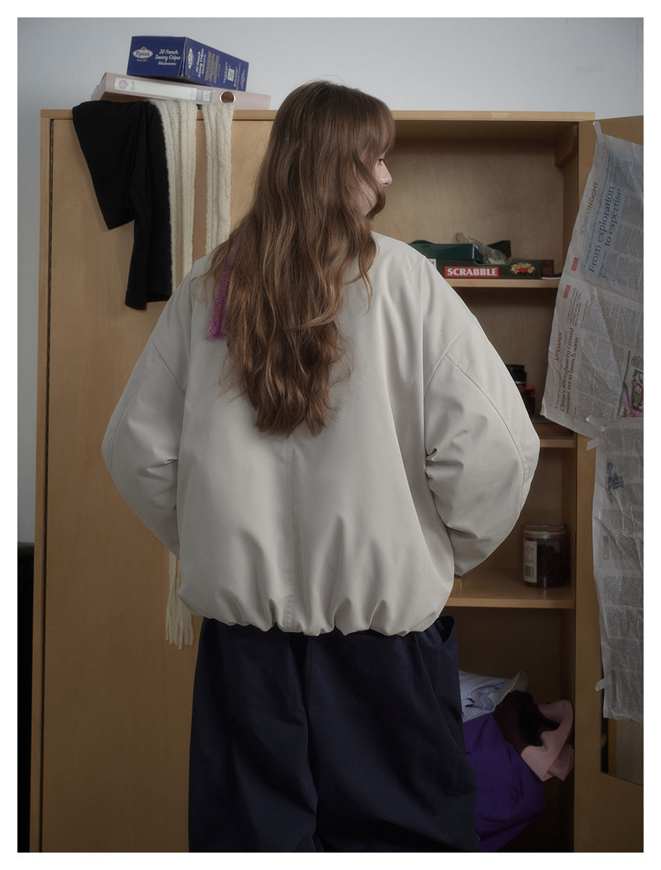 Back view of a model wearing a light gray bomber jacket with oversized sleeves and an elasticized hem.