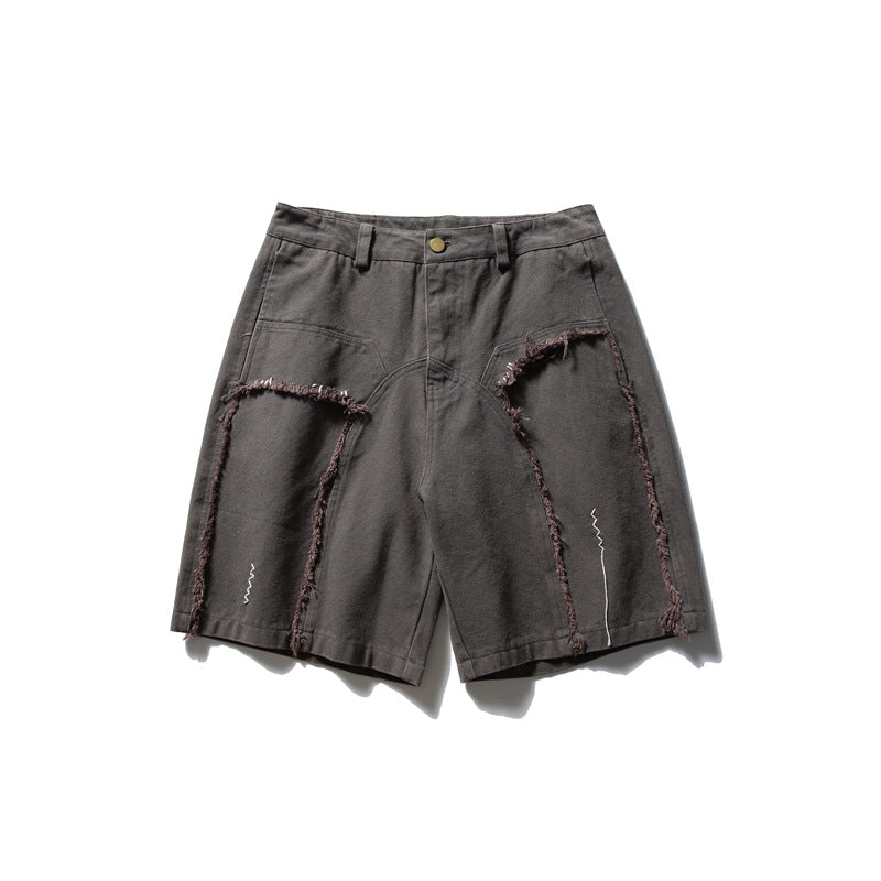 Dark gray knee-length shorts with frayed curved panel seams, white zigzag stitching and a raw hem, flat front view
