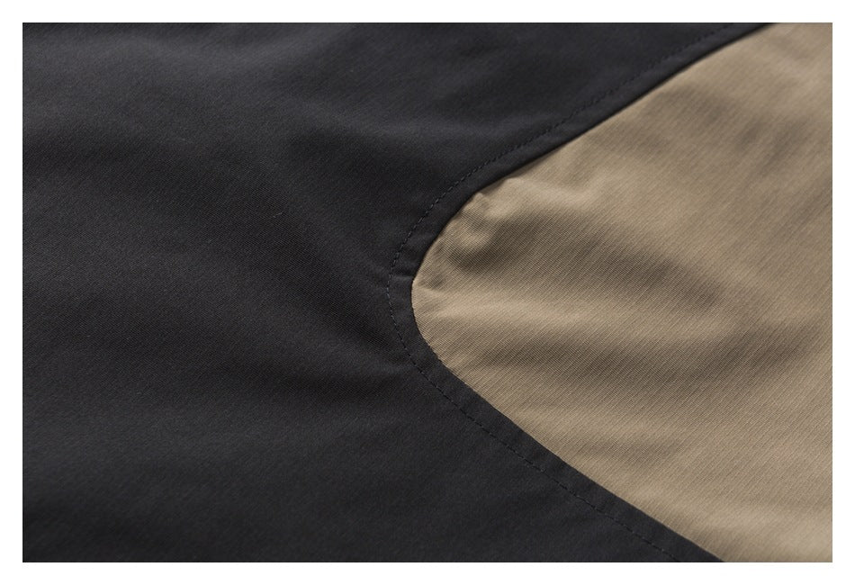 Close-up of a curved seam joining black and tan fabric panels.