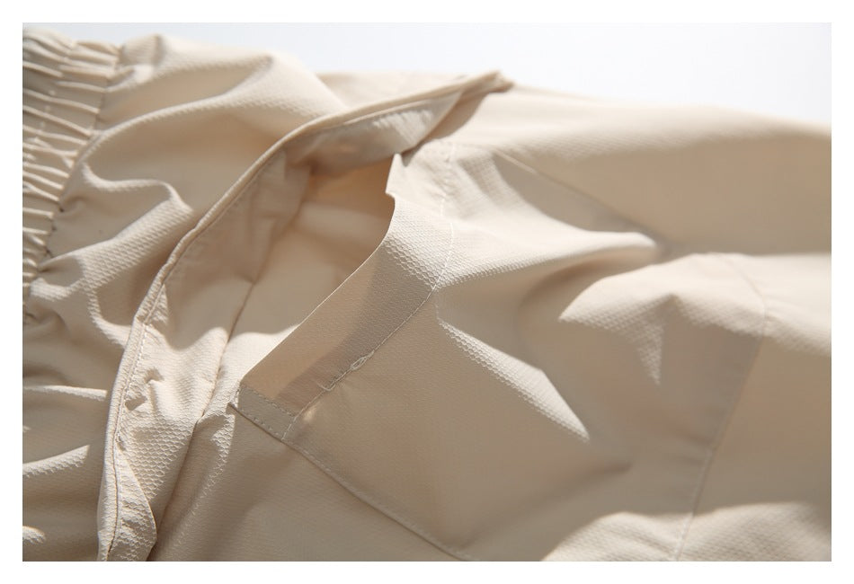 Close-up of stitching and layered fabric around a pocket on cream pants.