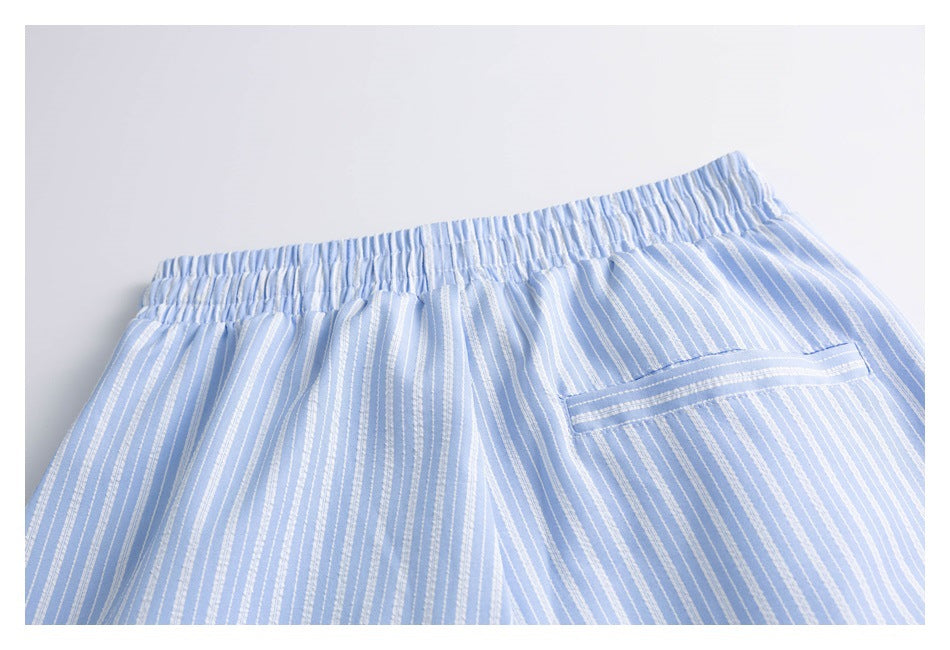 Close-up of the elastic waistband and rear pocket on light blue shorts with narrow white stripes.