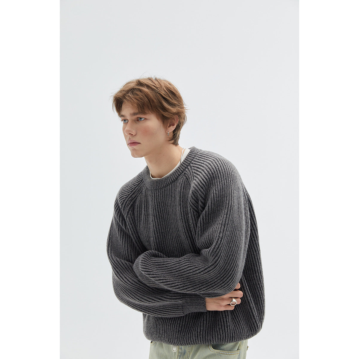Close view of a model wearing a charcoal ribbed raglan sweater with a crew neck and long sleeves.