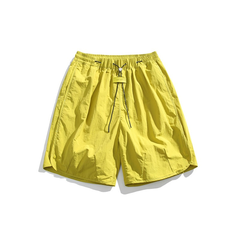 Bright yellow-green knee-length shorts with elastic drawcord waist and curved side hems, flat lay
