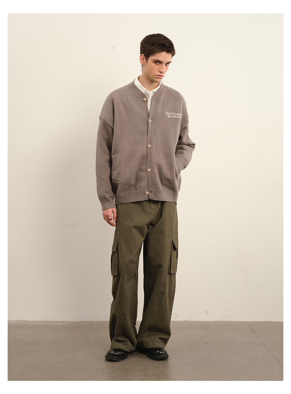 Model wearing a taupe-gray button-front knit cardigan over a white shirt with olive cargo pants, full-length view
