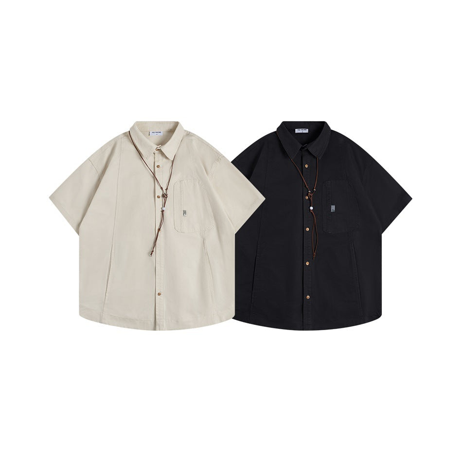 Two short-sleeve button-up shirts shown from the front, in cream and black, each with a chest pocket and brown cord detail.