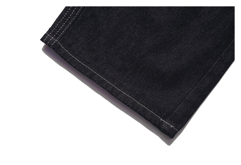 Close-up of a black denim jeans leg hem with visible stitching.