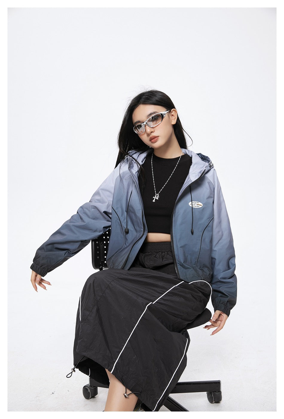 Closer view of a model wearing an open blue-gray gradient hooded jacket with a black top.