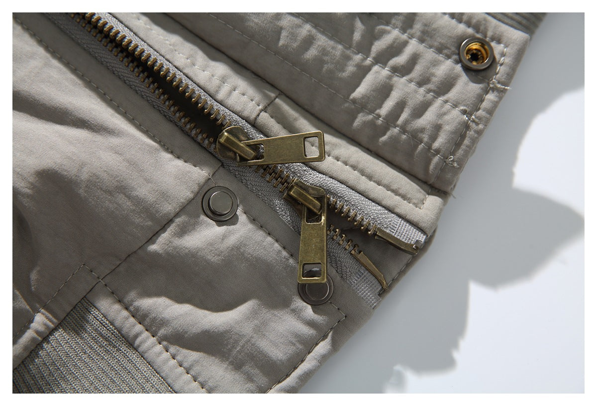 Close-up of a gray jacket with a metal zipper, snap fasteners, and stitched panels.