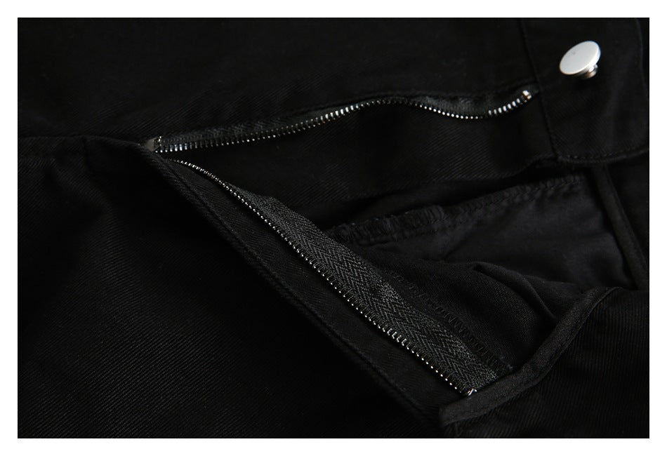 Close-up of black trousers with the fly open, showing a metal zipper and silver button.
