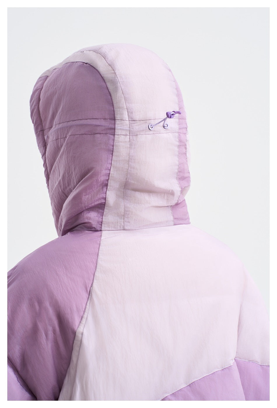 Close-up rear view of the lavender color-block puffer jacket, highlighting its hood and adjustment cord.