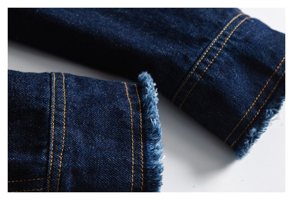 Close-up of dark blue denim hems with gold stitching and frayed edges.