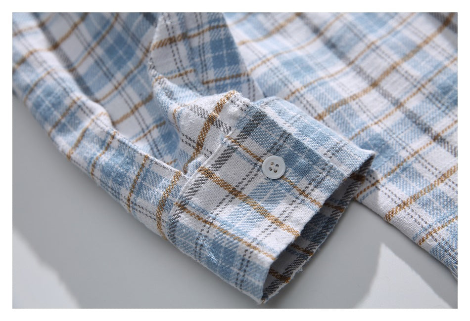 Close-up of a buttoned cuff on a light blue, gray, white, and tan plaid shirt.
