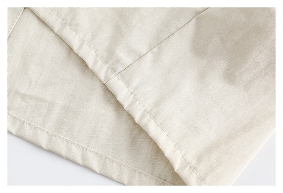 Close-up of an ivory garment's folded edge and parallel stitched seams.