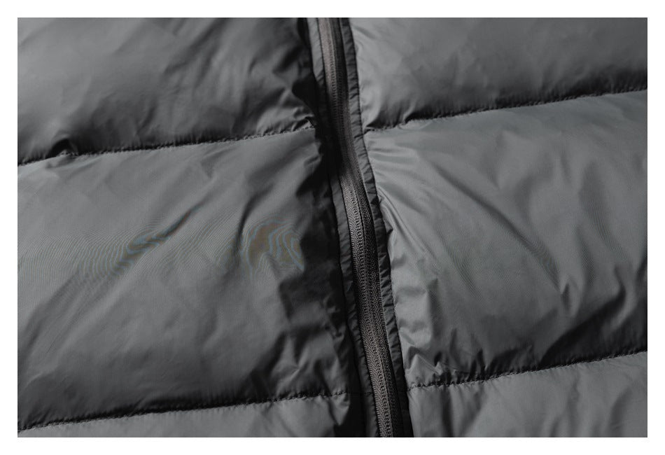 Close-up of the black front zipper and horizontal quilted panels on a dark gray puffer jacket.