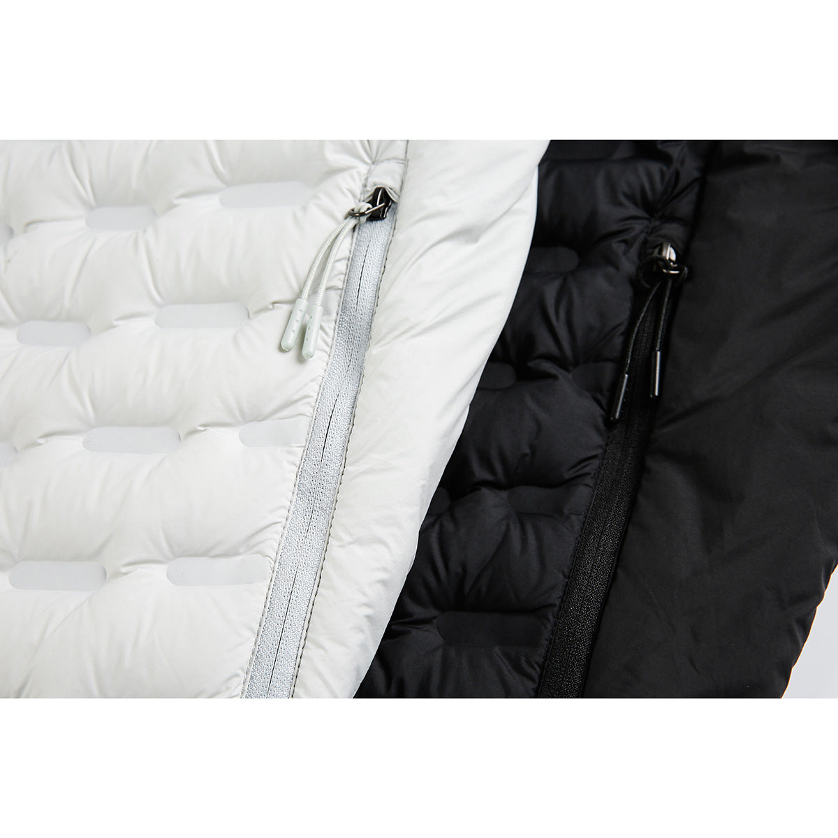 Close-up of white and black quilted jacket fronts, highlighting the zippers and zipper pulls.